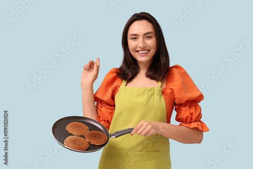 Happy young woman frying ta...