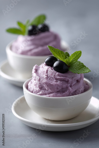 Delicious blueberry mousse dessert served in white bowls with fresh mint and berries