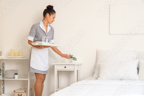 Pretty chambermaid placing ...