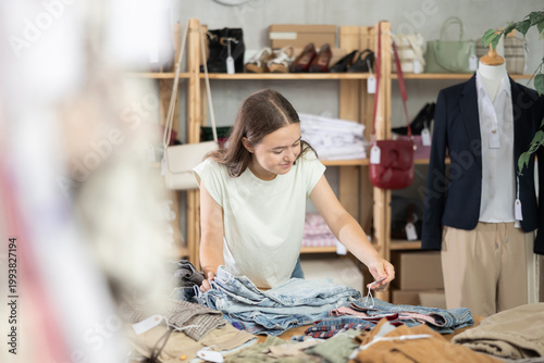 Tableau sur toile Teenage girl stands near a shelf with clothes and pants and chooses jeans