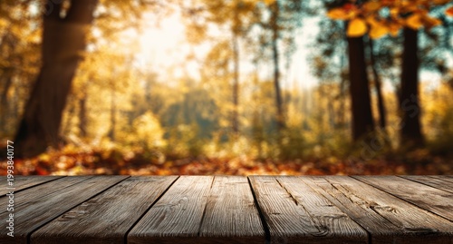 Rustic wooden table with a blurred, sunlit autumn forest background and colorful leaves
