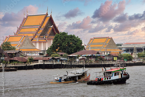 Tugs on the Chao Phraya River sailing past Wat Kalayanamit Woramahawihan, Bangkok, Thailand