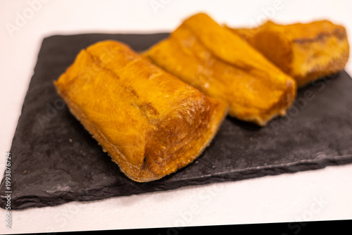 фотографія Delicious baked plantains served on a black stone plate in a kitchen setting at