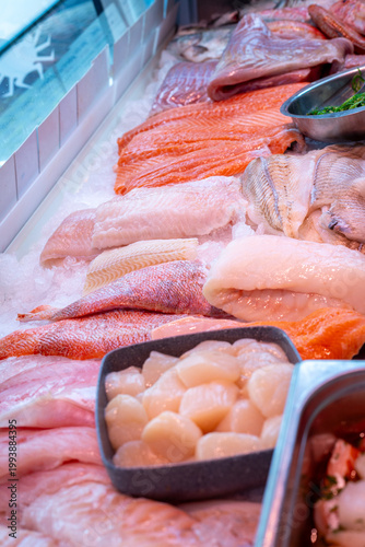 Fresh seafood display at a market with various fish and shellfish on ice in the afternoon sunlight