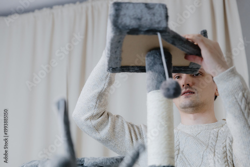 A young guy is assembling a new cathouse at home.