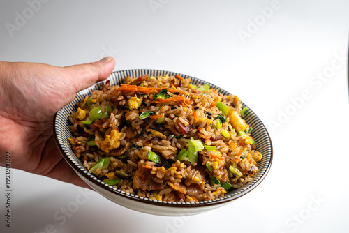 Fotografija A Hand Holding a Bowl of Fried Rice