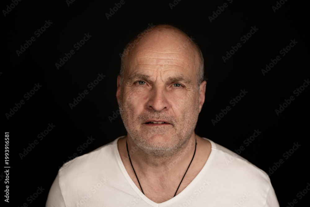 Obraz premium Middle aged man looking directly at camera with intense emotion against a black background