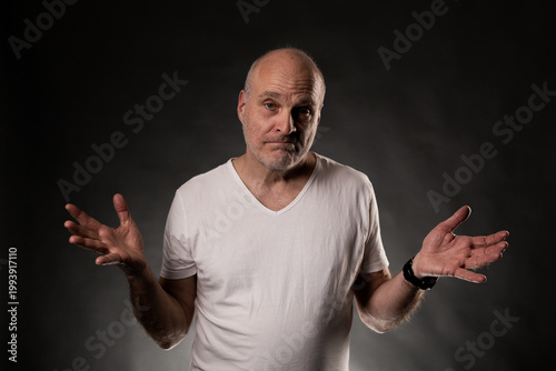 Confused bald man shrugging shoulders with open hands, showing doubt and ignorance