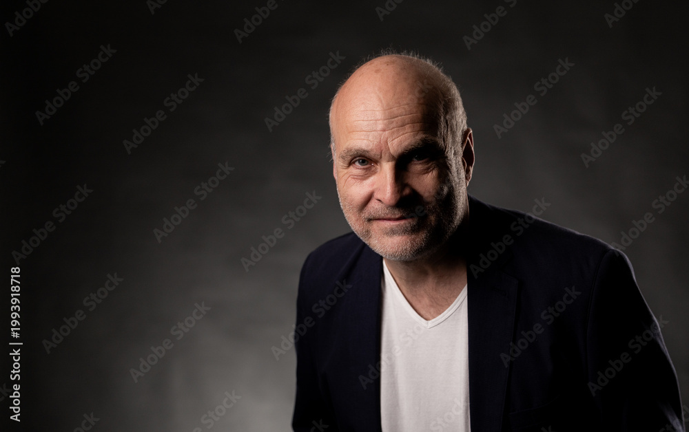 Fototapeta premium Senior bald man with stubble and a jacket looking directly at the camera