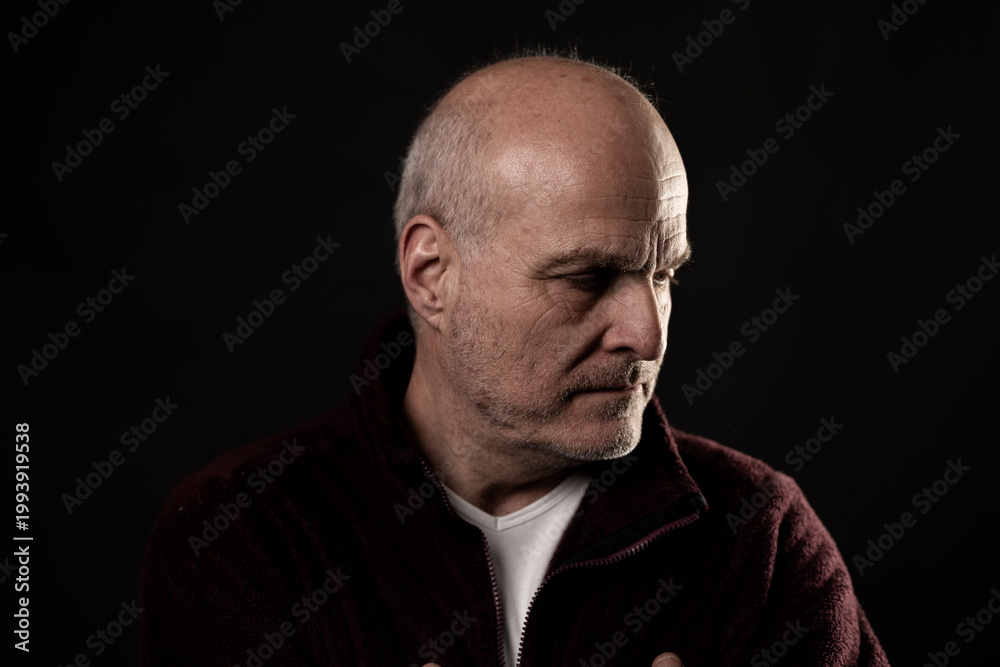 Obraz premium Mature man with stubble contemplating, captured in a low key studio setup
