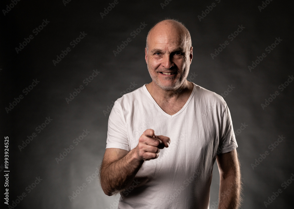 Naklejka premium Confident senior man choosing or motivating, wearing white t shirt on dark background