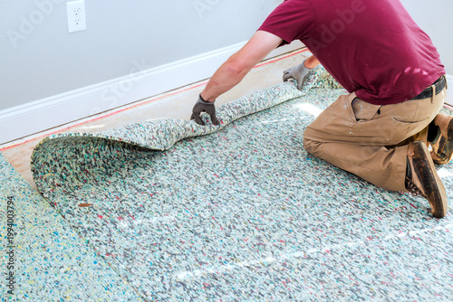 Tableau sur toile Worker pulls up piece of old carpet in room with light walls wood floor