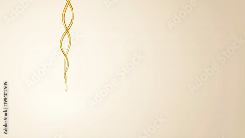 Thin golden liquid stream dripping down on cream textured background with copy space