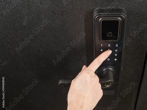 A woman opens a modern smart door lock with a digital keypad using a code.