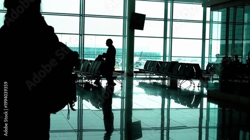 Silhouettes of a traveler walking through a modern airport terminal at dawn