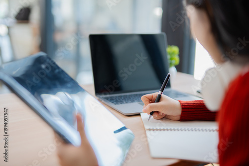 A smiling female student wears headphones and chats online using a laptop.