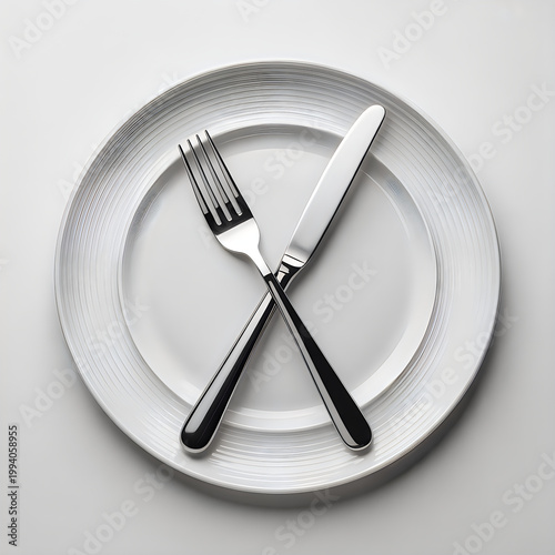 Minimalist table setting with a white plate and crossed silver cutlery set