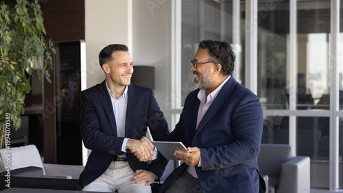Fotografi Two businessmen expressing respect, handshaking during workday in office