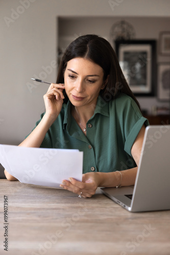 Konstfotografi Focused adult woman sits at desk, reading documents text, analyzing details, rev