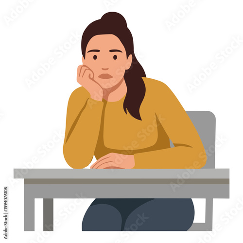 A woman sits bored alone at a desk indoors looking sad