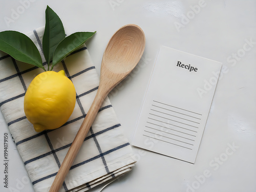 Lemon with leaves, wooden spoon and recipe card on checkered napkin