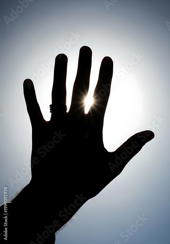 Silhouette of a hand reaching towards the sun with a starburst effect