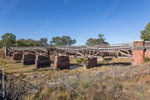 An old railway bridge called Sunnyside rail bridge, stands in a state of collapse and disrepair, and is fenced off for safety reasons as it spans Tenterfield Creek in New South Wales, Australia.  