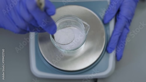 Laboratory technician adding precise measurements of chemical compounds using digital balance in research facility