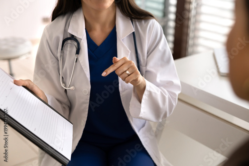 Closeup doctor discussing treatment plan, reviewing medical report, explaining diagnosis results on clipboard, providing healthcare services to patient during clinic visit. Health checkup consultation