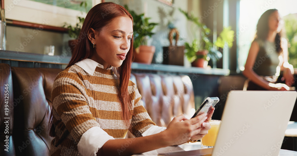 Fototapeta premium Woman, phone and laptop in restaurant with remote work, email and social media marketing notification. Freelancer, person and typing in cafe with tech, mobile app and website for online advertising.