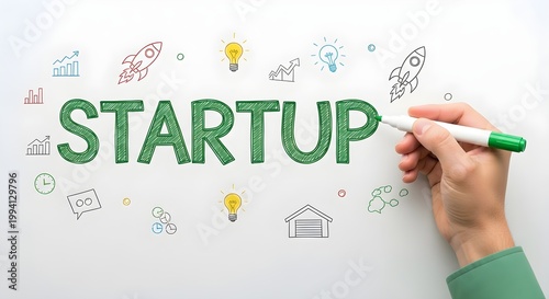 Hand writing startup concept with green marker on whiteboard with business icons around  entrepreneurship and innovation