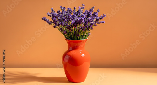A bouquet of lavender in a bright orange ceramic vase against an orange background; a minimalist floral still life featuring vibrant colors, soft shadows, and space for text. AI generated.
