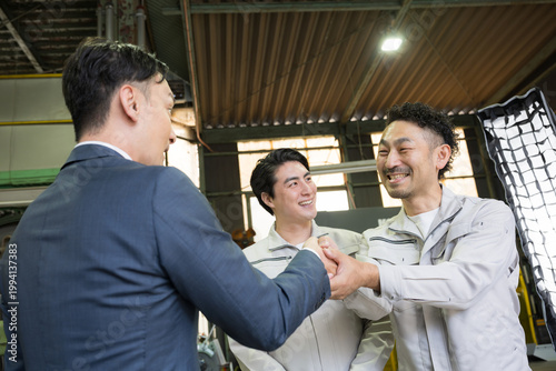 製造業の工場で握手する営業マンと作業員の信頼関係ビジネス契約や合意シーン　業務提携、協力、融資などのbtobの法人営業イメージ