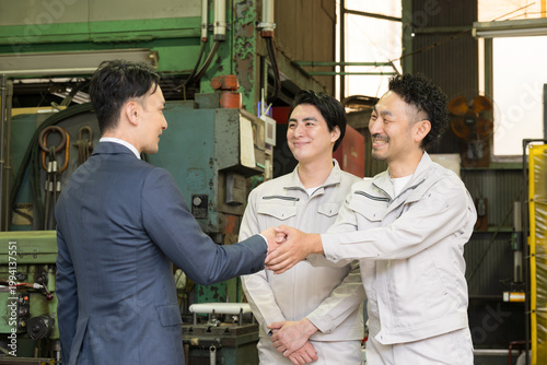 製造業の工場で握手する営業マンと作業員の信頼関係ビジネス契約や合意シーン　業務提携、協力、融資などのbtobの法人営業イメージ