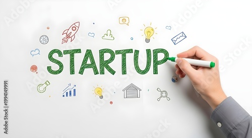 Hand holding a green marker pen writing the word STARTUP surrounded by colorful handdrawn business concept icons and symbols on a white background