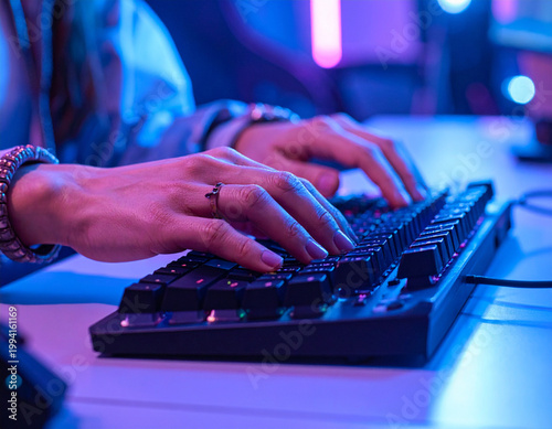 Hands typing on illuminated computer keyboard
