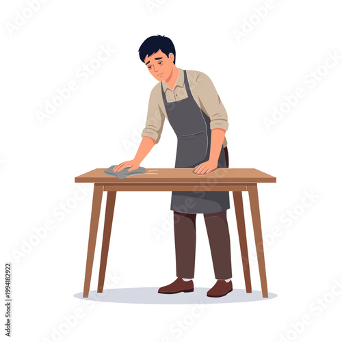 Man in apron wiping down a wooden table with a cloth indoors