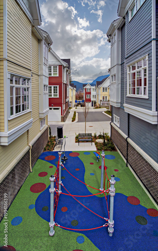 Small playground space in residential area of townhouses with cloudy sky background