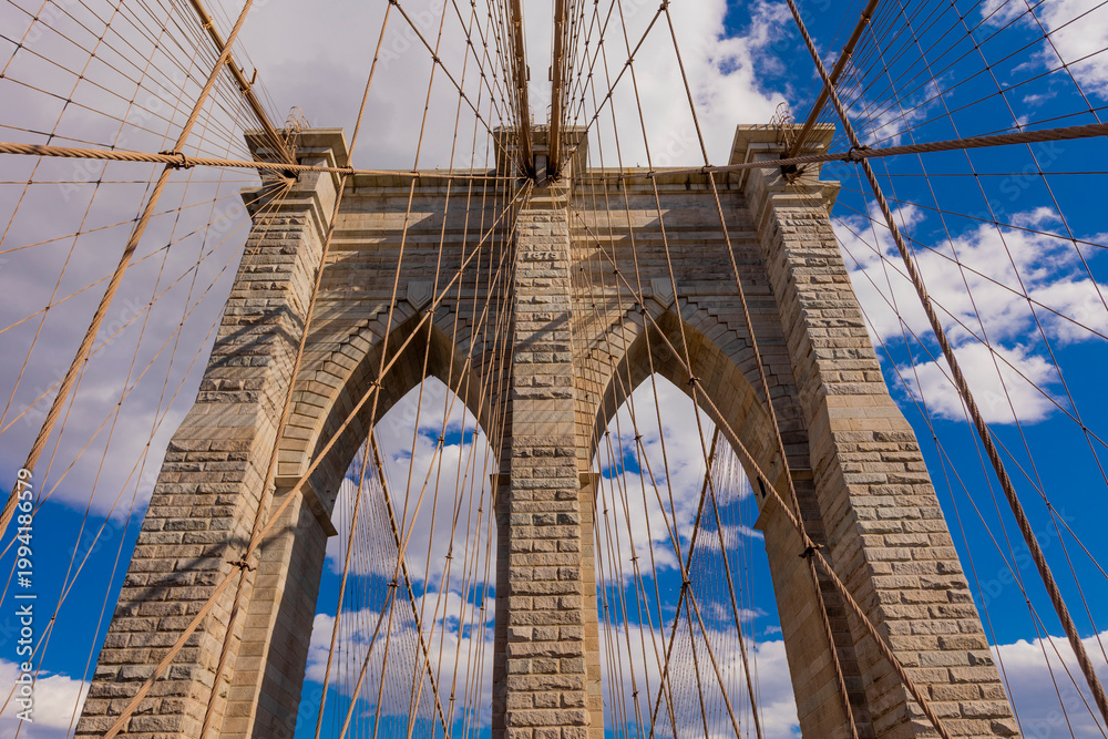 Obraz premium Majestic Brooklyn Bridge stands tall against a vivid blue sky in New York