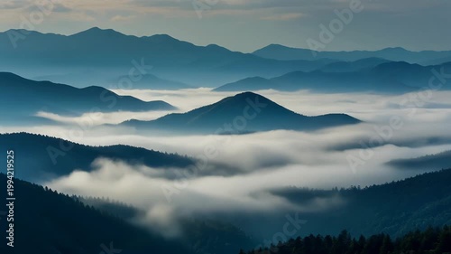 Fog covers rolling hills and mountains in a serene landscape view.