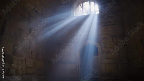 A beam of light shines through a small window in an ancient stone building with a door.