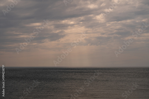 Overcast sea horizon with grey cloud and ray of light breaking through