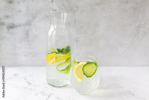 Healthy detox water with lemon, cucumber and mint on white marble.  Bright, airy, and minimalist aesthetic, perfect for wellness, hydration, and healthy lifestyle concepts. 
