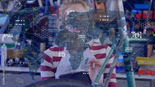 Tech holding tablet behind bike wheel, tapping and activating map HUD while checking repair data