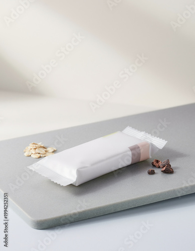 A wrapped chocolate bar with nuts and chocolate chips on a gray cutting board indoors
