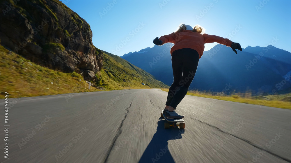 Obraz premium woman skateboarding and making tricks between the curves on a mountain pass.