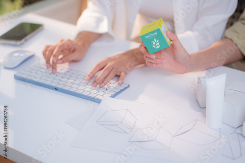 Hand holding cosmetic packaging mockup box, graphic designer and development branding project, sketch and layout artwork, business startup planning creative for skincare product label advertising.