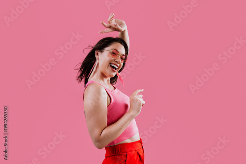 Happy woman dancing with joy on pink background