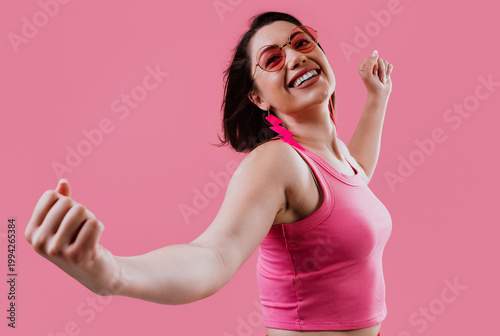 Happy woman dancing expressing joy and freedom on pink