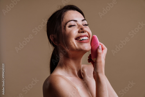 Woman smiling using electric facial cleansing brush